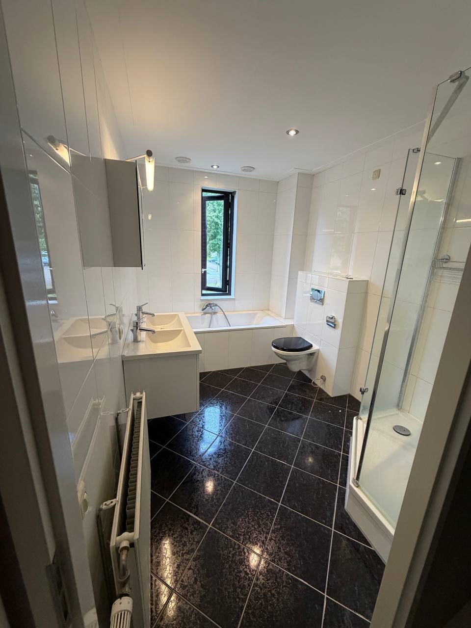 Witte badkamer met ligbad en losse douchecabine voor de renovatie